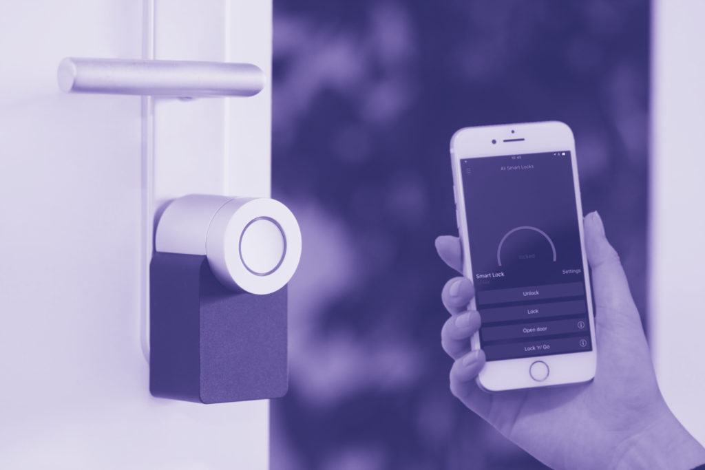 A person holds a smart phone up to a smart lock